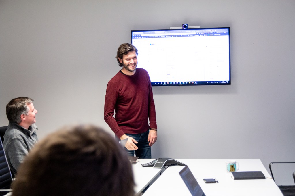Man presenting in front of a screen to other group members